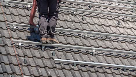 technician drilling single axis base for installation of solar panels on rooftop of house