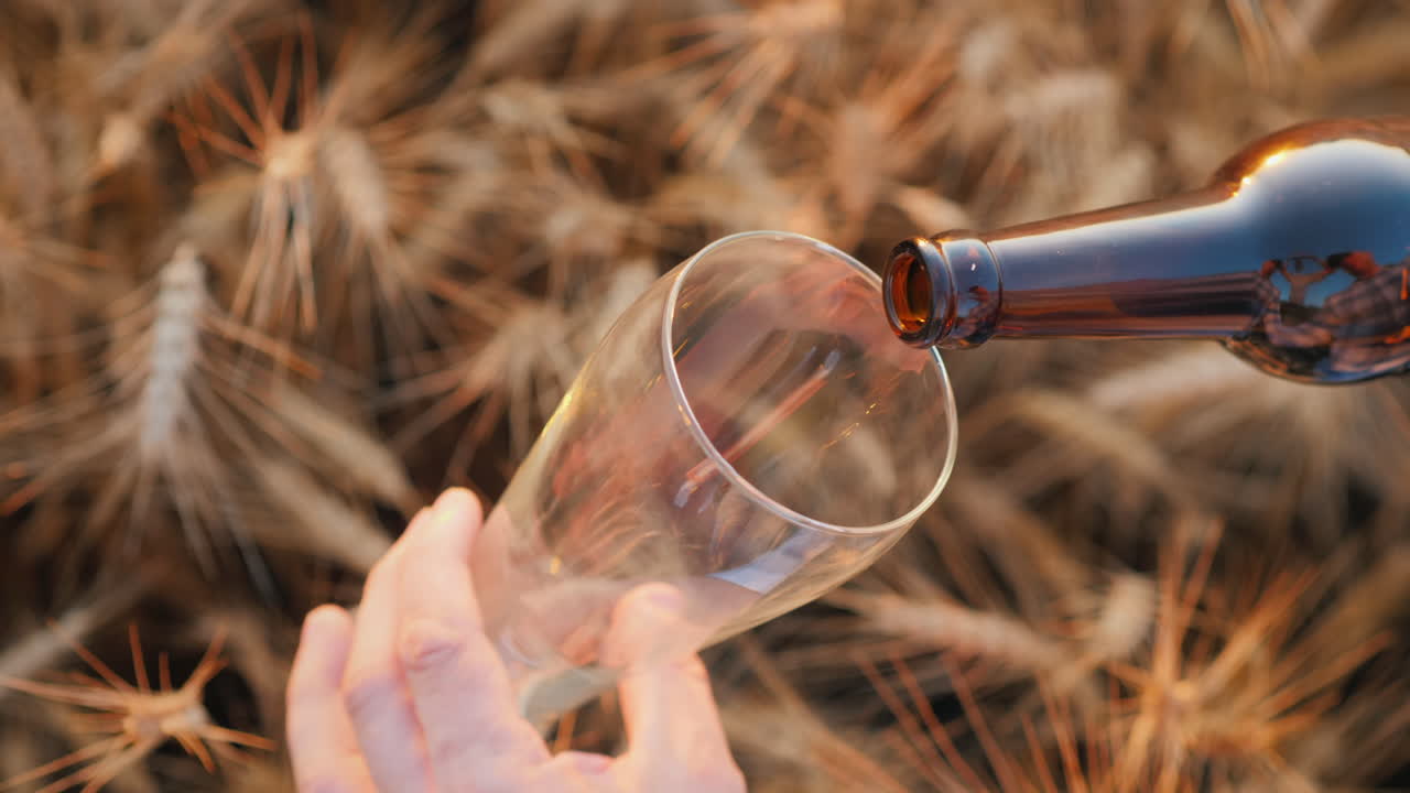 Un uomo versa la birra da una bottiglia in un bicchiere.