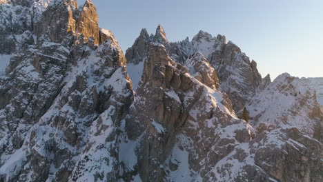 rocky snowy sunlit tre cime mountain peaks aerial reversing view away from summit