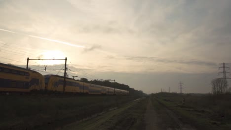 train passing through rural dutch landscape at sunrise/sunset