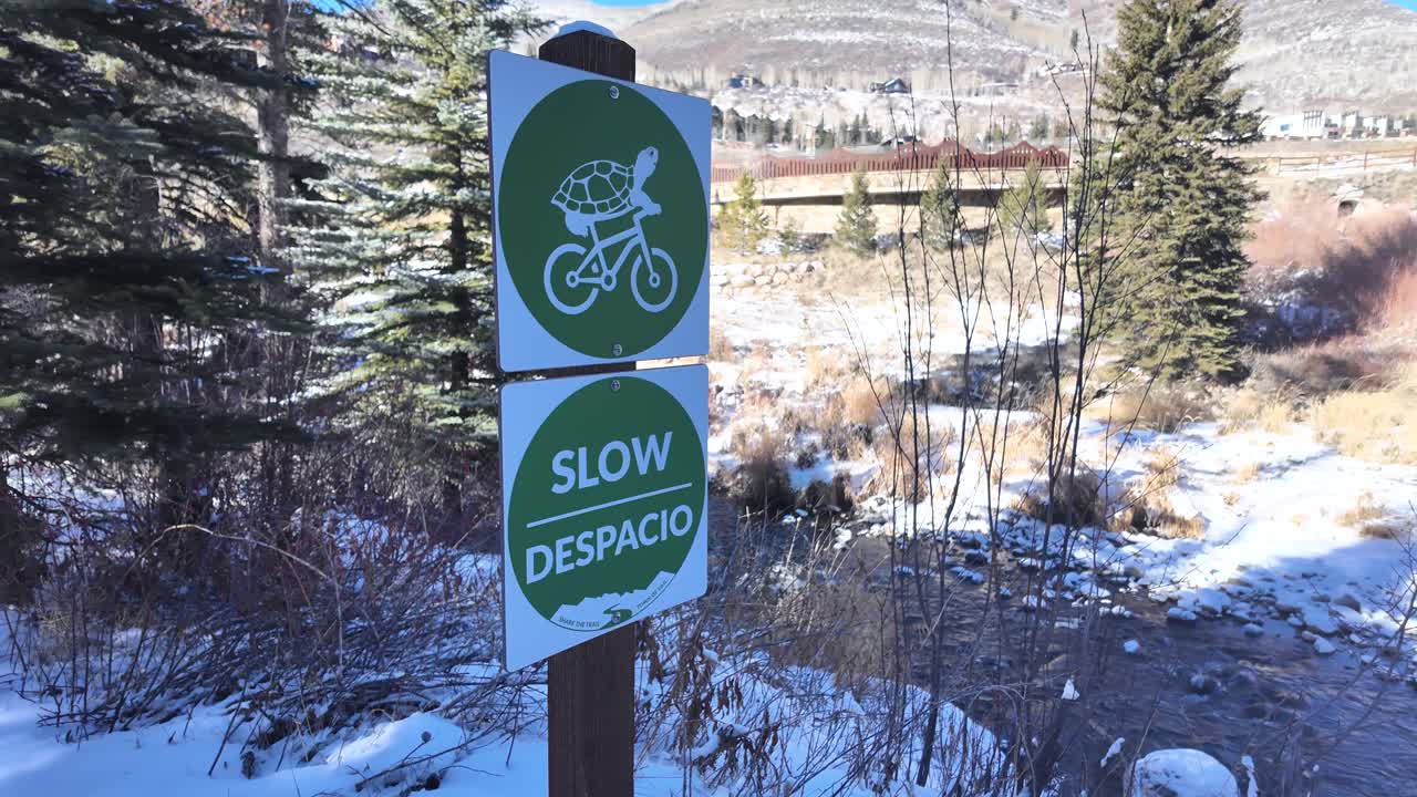 Panorami suggestivi lungo il sentiero Gore Creek a Vail, Colorado, USA. Un cartello chiede ai ciclisti di rallentare mentre si avvicinano a una ripida riva del fiume.