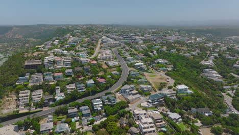 Backwards-fly-above-urban-borough-with-residences-and-vacation-houses-at-seaside.-Plettenberg-Bay,-South-Africa