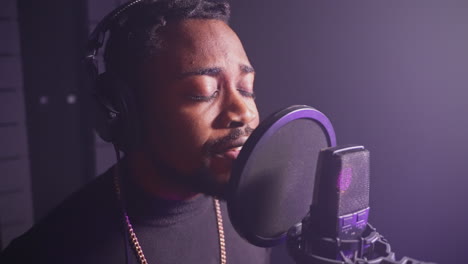 man singing into microphone in recording studio