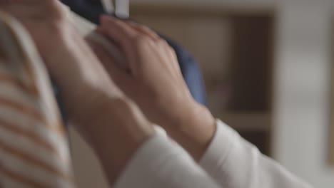 close up of woman at home choosing business suit from clothes rail for job interview