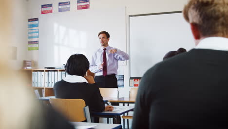 teenage students listening to male teacher in classroom