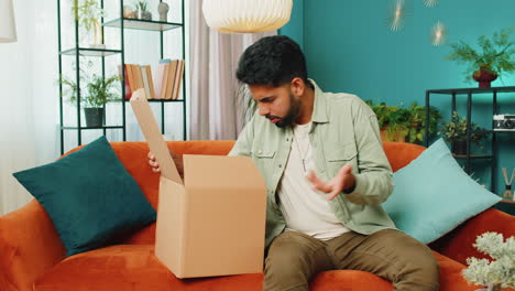 comprador enojado insatisfecho hombre indio desempaquetando el paquete sintiéndose molesto, confundido, entrega equivocada
