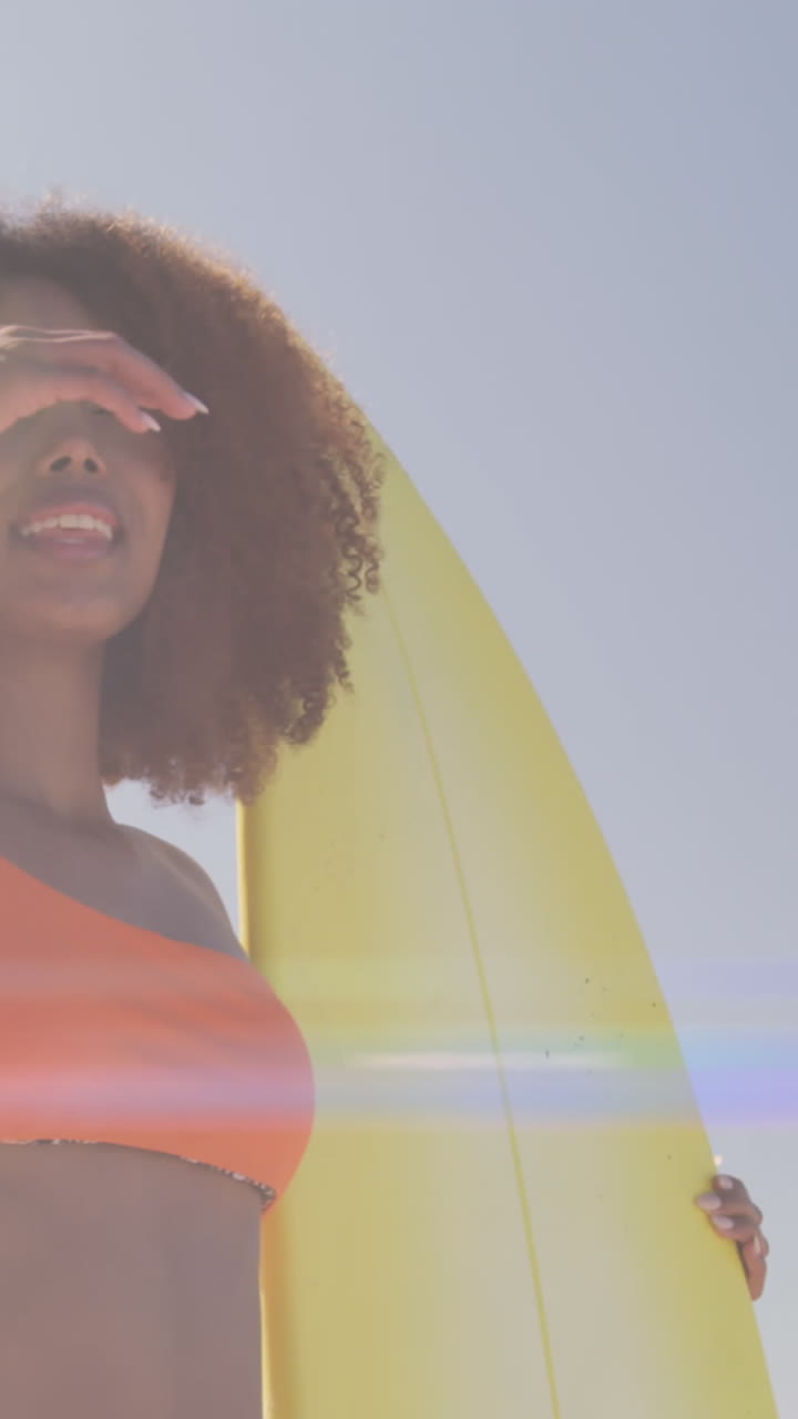 Animation of lights over african american woman holding surfboard