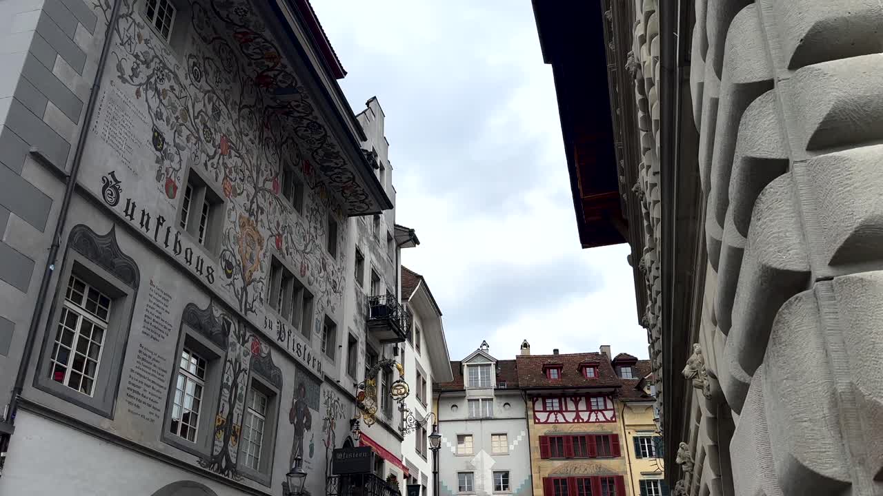 People walking on historic stairs in Lucerne, Switzerland, surrounded by traditional painted buildings