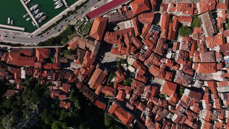 kotor town houses and marina by the bay of kotor on a sunny day in montenegro. - aerial shot
