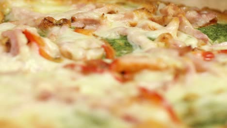 close-up of a pizza with ham, peppers, and pesto