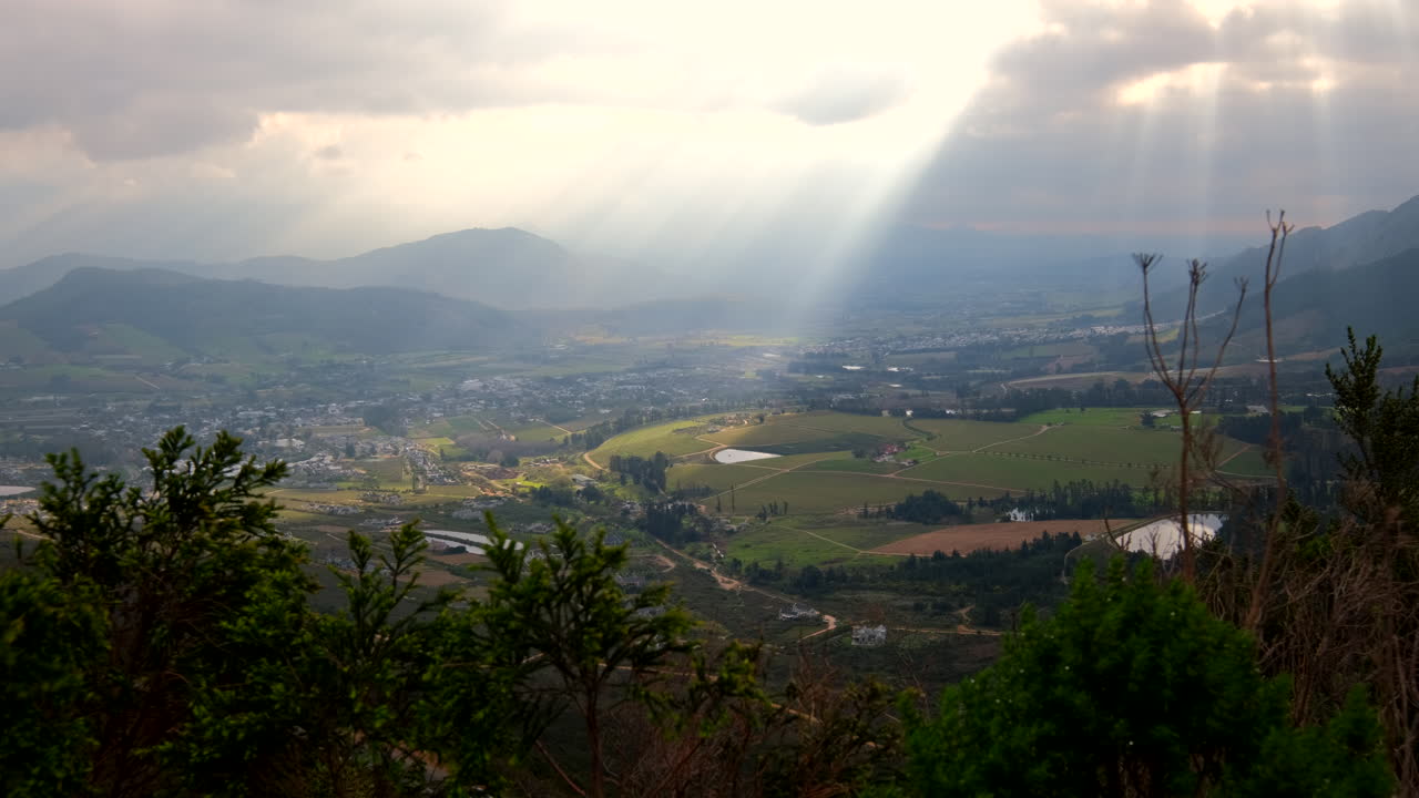 Picturesque crepuscular rays lighting up Franschhoek Cape winelands farm lands