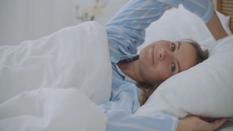 mujer durmiendo en una cama cómoda. mujer despierta levantarse estira las manos en la cama se siente saludable