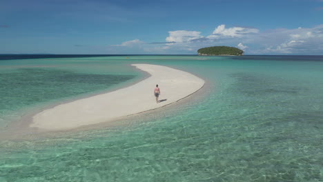 man walking on a beautiful sandbar in the turquoise waters of the philippines