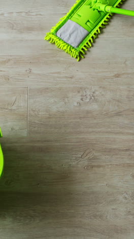 cleaning the house. green bucket and mop on the parquet floor. microfiber brush is mopping the floor. householding tools. top view. vertical video