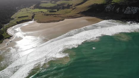 Seaside-of-New-Zealand-South-Island-aerial,-the-beach,-cliffs-and-green-saddle-panorama,-warm-summer-day