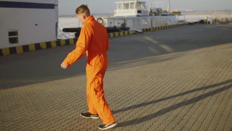 Young-harbor-worker-in-orange-uniform-is-turning-around-in-the-son.-Happy-young-man-is-celebrating-something