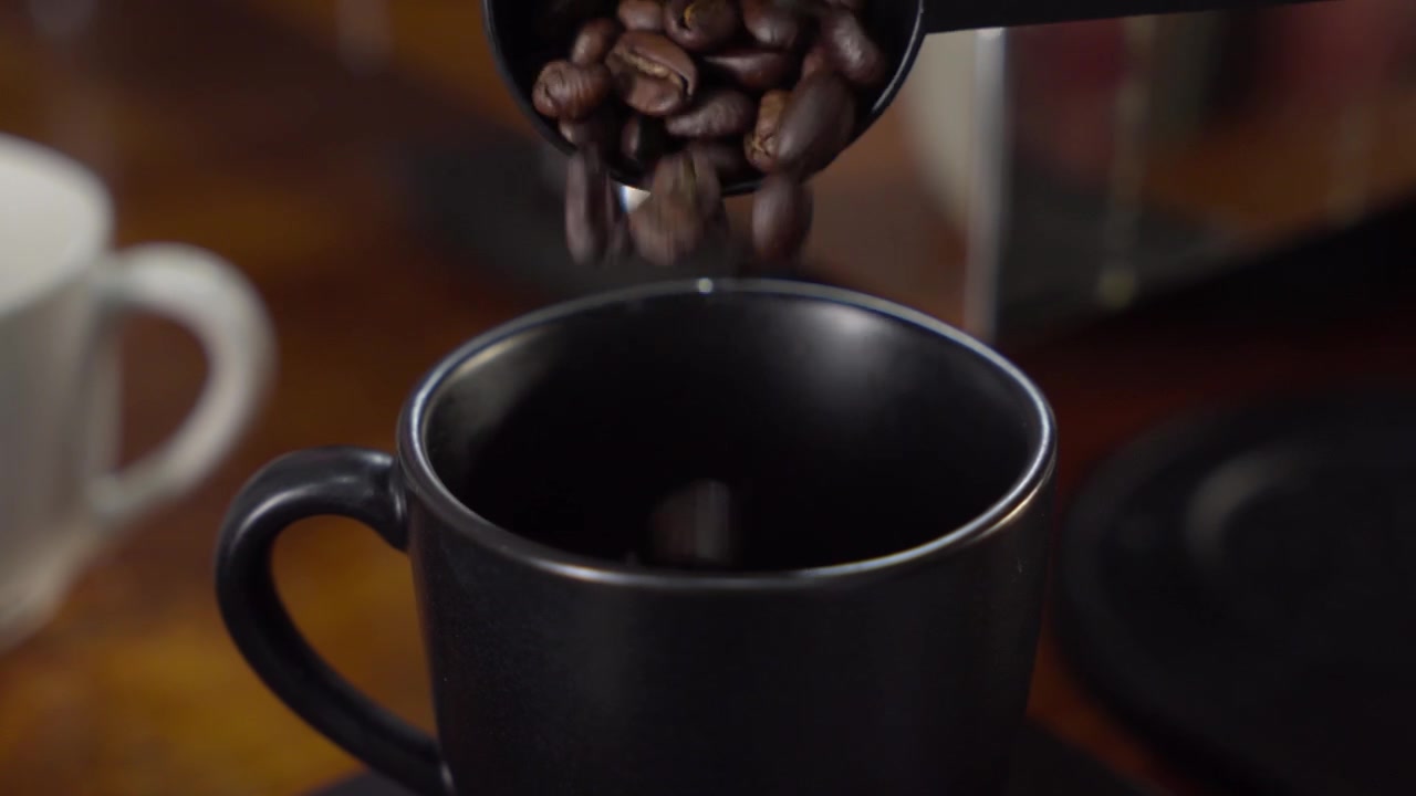 Hælde kaffebønner i kop nærbillede, koncept for dosering og kaffetilberedning.