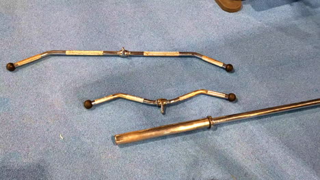 closeup of various chrome gym equipment attachments on floor in indoor fitness center