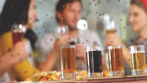 animación de manchas oscuras contra el primer plano de cuatro vasos de tiro en la mesa de la barra