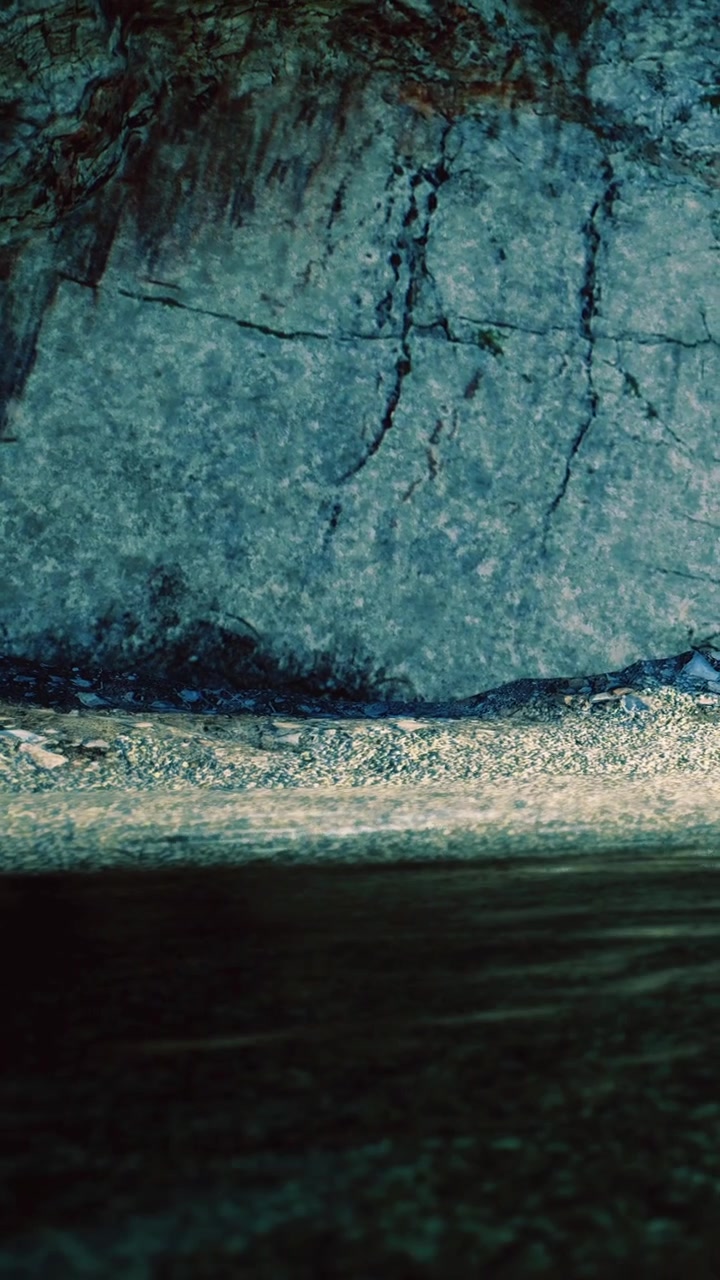 Mysterious reflections dance on serene waters under rocky shadows