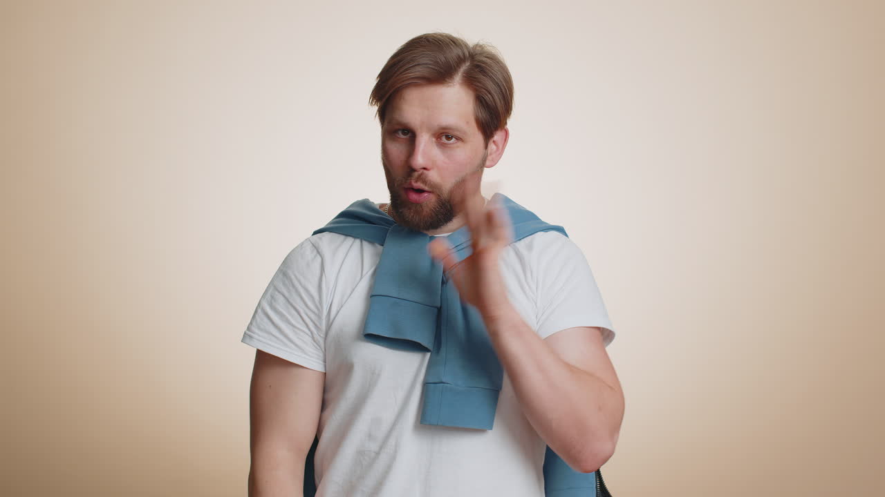 Young bearded man presses finger to lips makes silence gesture sign do not tells secret stop gossip