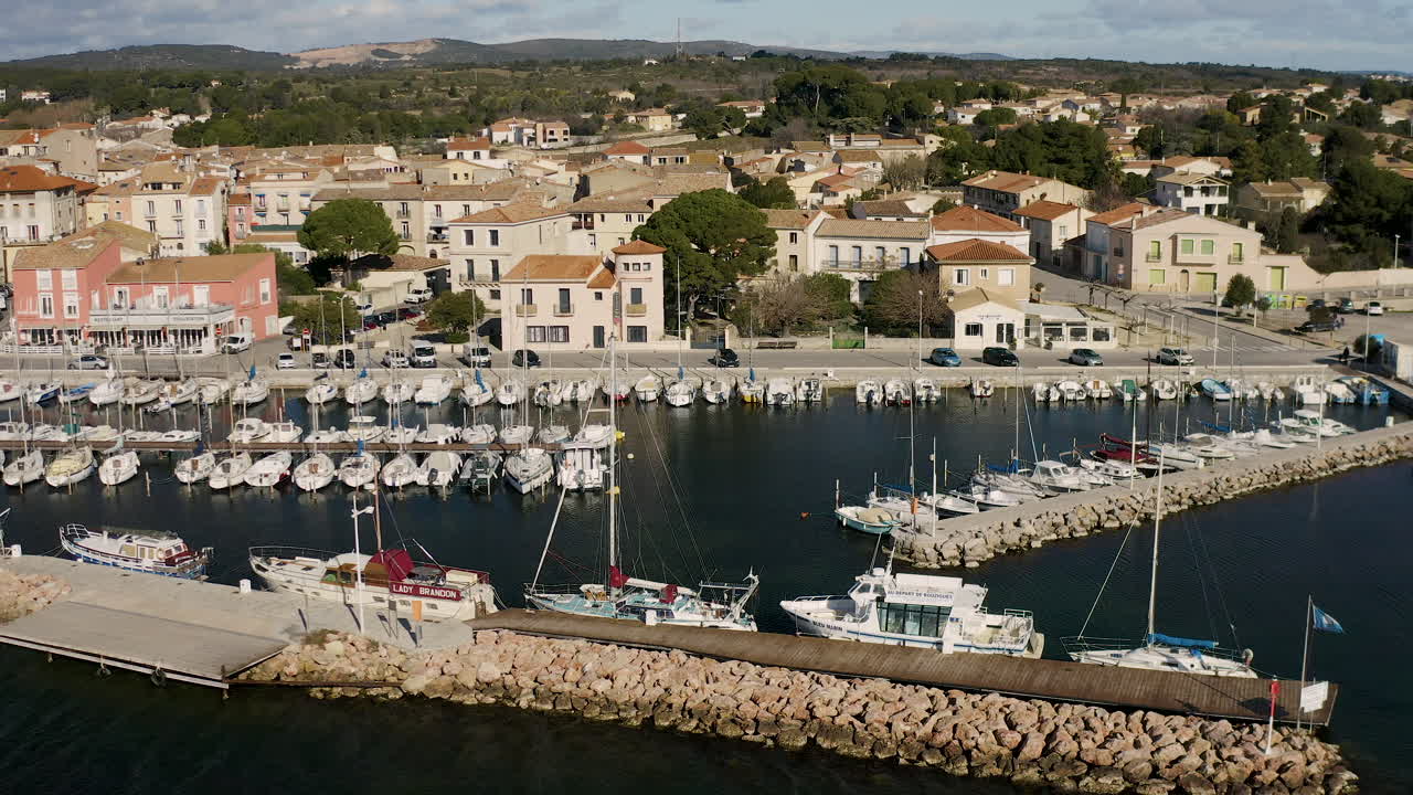 de izquierda a derecha viajando sobre el puerto de bouzigues, barcos de vela de día soleado y la ciudad vieja.