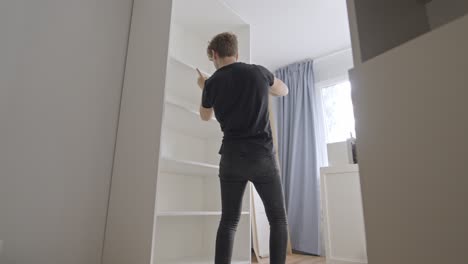 young craftsman assemble modern white closet inside home
