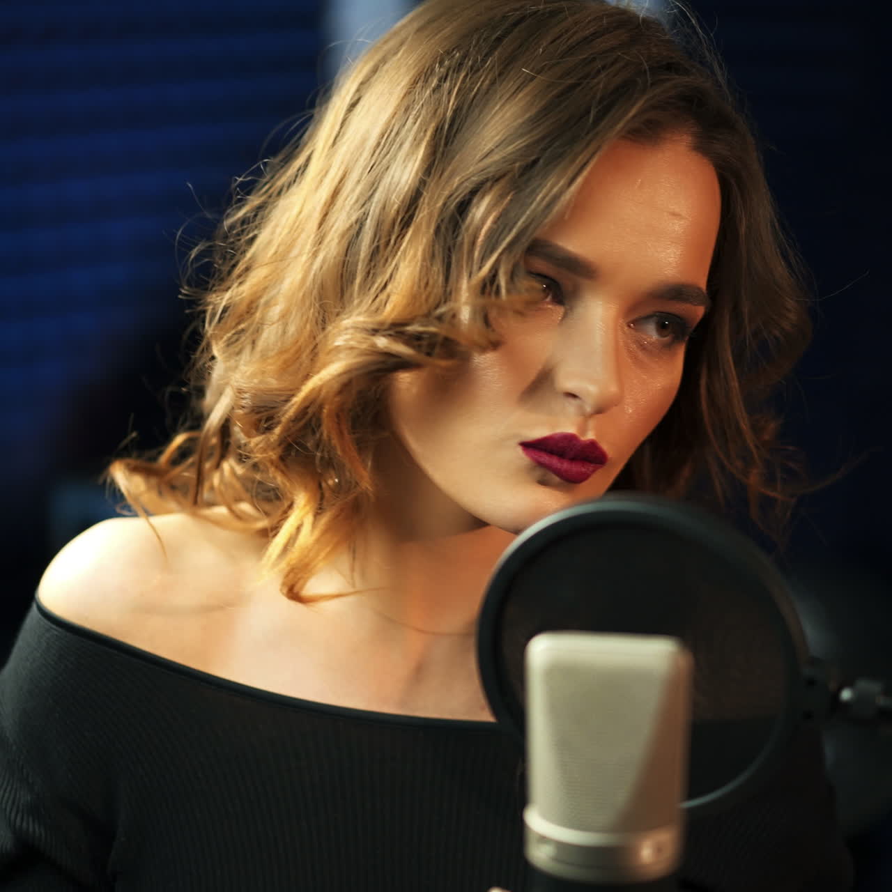 Young girl singing into a microphone in a studio. Close-up of a singer. Square video