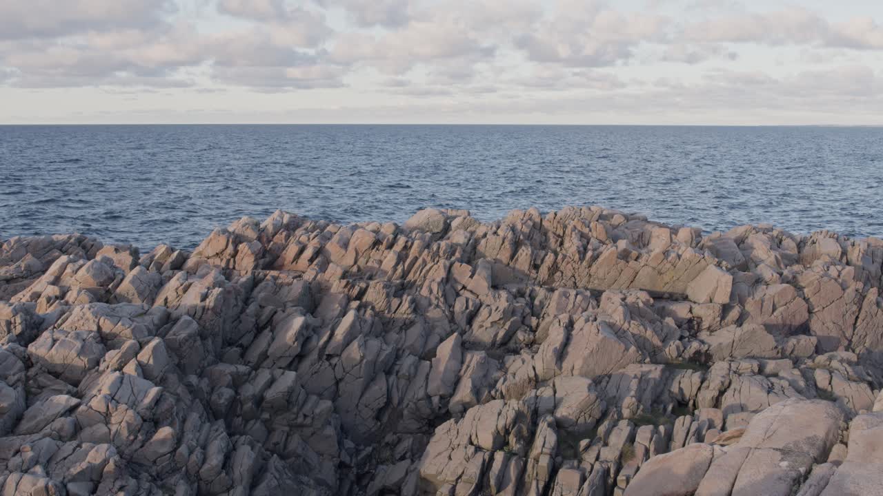 일몰 때 전경에 놀라운 바위 곶이 있는 푸른 영원한 바다 지평선