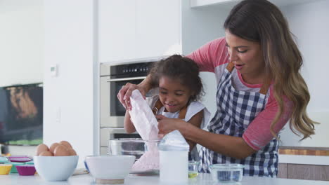 hispanic mother and daughter having fun in kitchen baking cake together