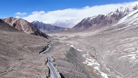 aerial drone shot showing a vehicle driving past scattered settlements and prayer flags in ladakh.