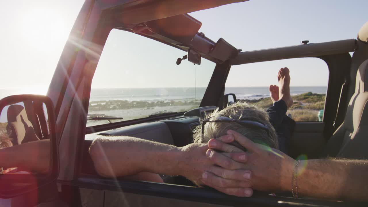 해변에서  ⁇ 은 날에 휴식을 취하는 차에 누워있는 편안한 백인 남성