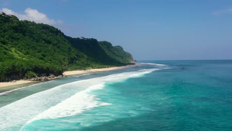 tropical turquoise blue ocean waves along mountain coastline beach of nyang nyang in uluwatu bali on sunny day, aerial