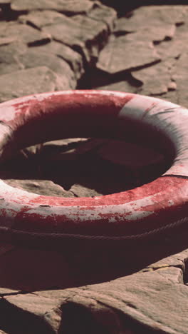 a red and white life preserver on a rocky shore