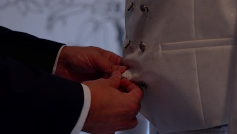 groom getting ready: buttoning his wedding vest