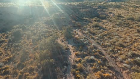 drone shot following cyclist people on a bicycle race going downhill in the desert mountains