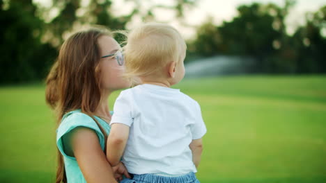 adorable kids standing in green field. elder sister holding brother on hands