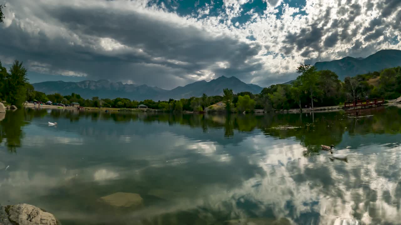 paisaje nublado sobre el estanque y las montañas con las nubes dinámicas reflejándose en la superficie del agua - lapso de tiempo estático