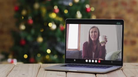 feliz mujer mayor caucásica en videollamada en computadora portátil, con decoraciones de navidad y árbol