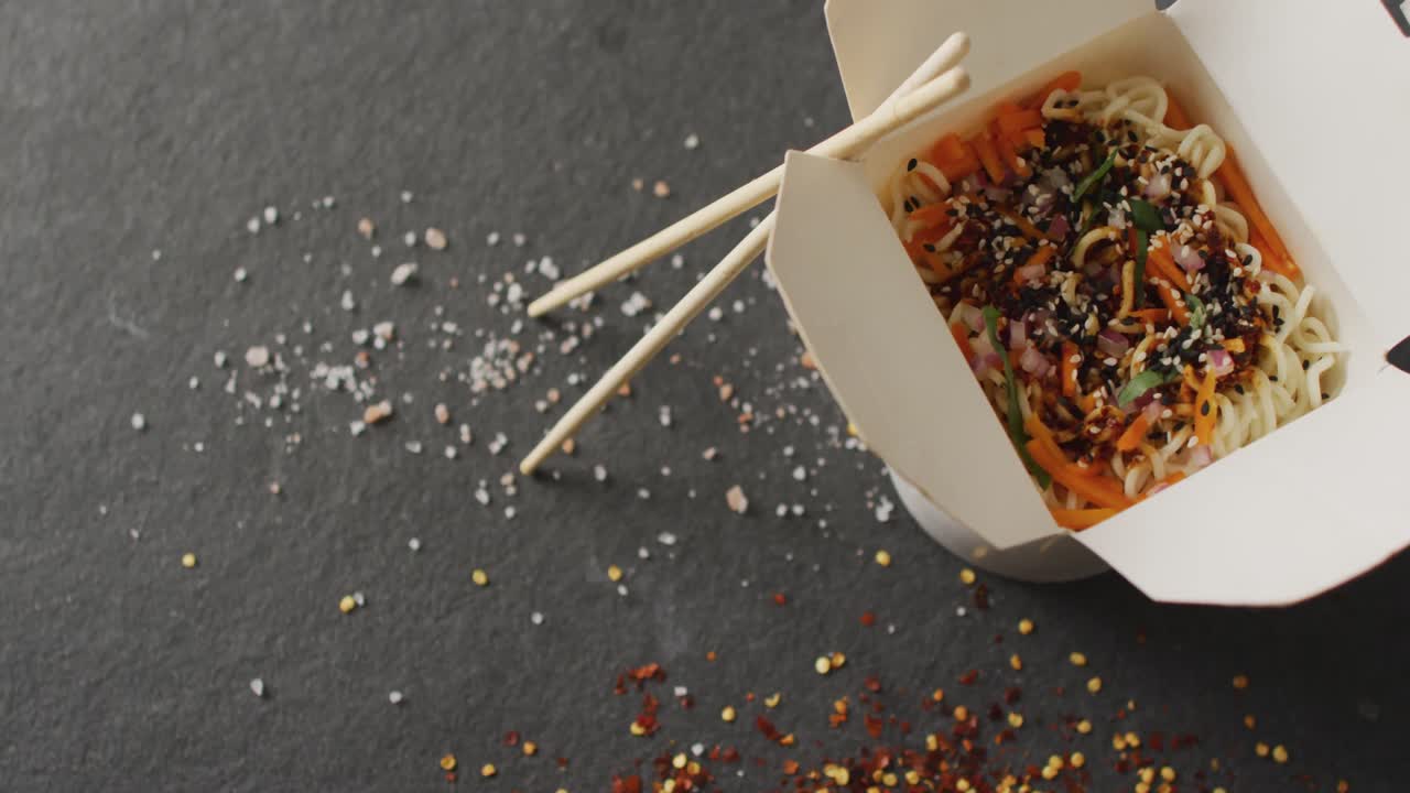 Composition of box of pad thai with chopsticks on black background