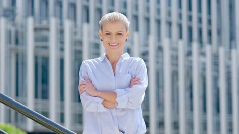 a woman with short blonde hair smiling in front of a modern building