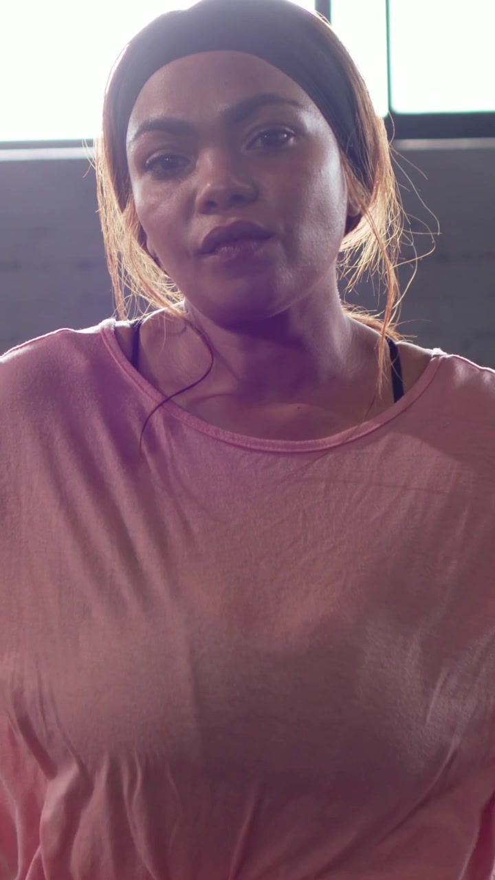 Vertical video: Reacting to camera pull woman in pink top shifting hands adjusting posture at bench