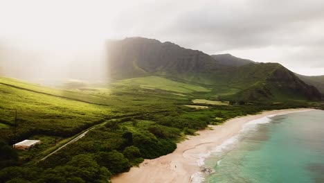 Hermosa-Toma-De-Drones-De-4k-Que-Recorre-La-Costa-De-La-Playa-De-Makua-En-El-Lado-Oeste-De-Oahu-Con-Los-Rayos-Del-Sol-De-La-Mañana-Derramándose-Sobre-Las-Montañas-Verdes