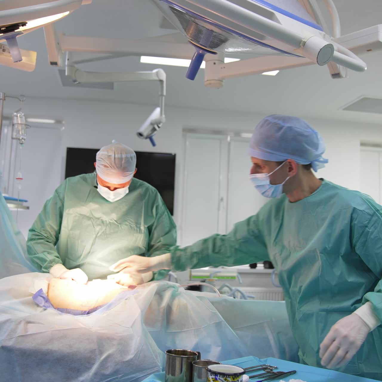 Doctor performs an operation of liposuction. Surgeon gathering fat of the abdomen during plastic surgery. Cosmetic surgery and improvement for a patient's body