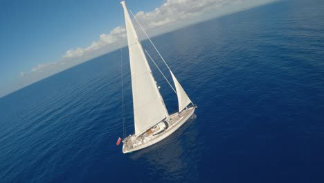 Fpv-aerial-orbiting-shot-of-white-luxury-sailing-yacht-during-sunny-day-and-blue-sky