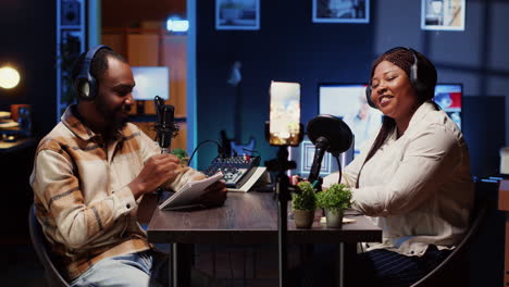 vlogger show host and guest using smartphone on tripod to record discussion in studio