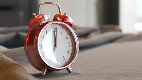 Old-vintage-red-alarm-clock-standing-on-a-wooden-office-desk.-Bells-ring-and-clock-shakes-on-time.-Office-workstation-in-a-background.-Symbol-of-morning,-countdown,-deadline.--Classic-ageless-design.