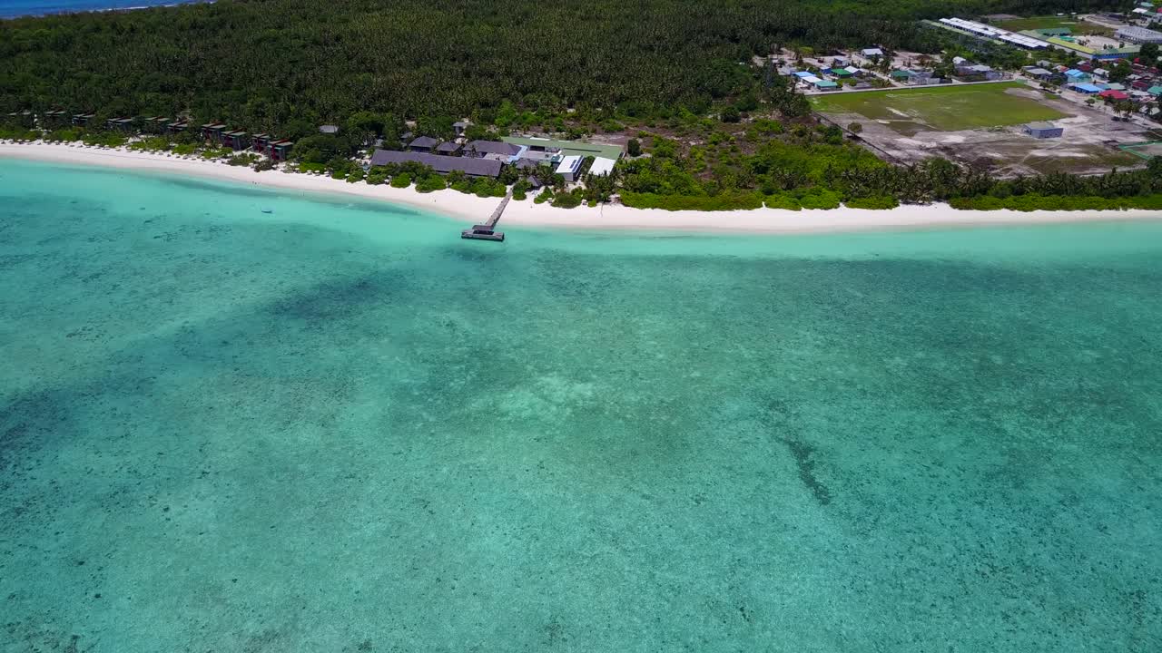 toma aérea amplia del prístino océano maldivo, resort y pueblo isleño