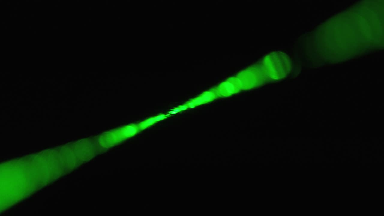 rayo láser verde sobre un fondo negro. rayo láser de potencia que brilla en la niebla