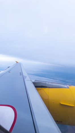 view from a plane window of the sky with the wing of the plane in shot in vertical